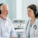 Un homme de 65 ans consulte une médecin ORL dans une salle lumineuse, avec un casque de test auditif et un audiomètre visibles.