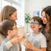Une opticienne échange chaleureusement avec une mère et son jeune garçon dans un magasin d’optique lumineux, tandis que l’enfant porte une monture de lunettes colorée.