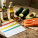 Nature morte réaliste montrant sur une table de l’huile d’olive, de l’huile de colza, des noix, un avocat et du saumon, accompagnés de cartes nutritionnelles vierges, éclairée par une lumière naturelle douce.
